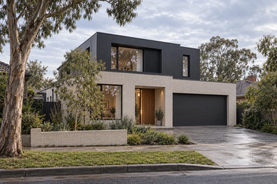 A pale-brick two-storey home framed by eucalyptus in soft morning light